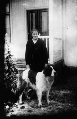 kvinna stående med hund framför veranda till byggnad.
Nyckelord: Hund Veranda Bostad
