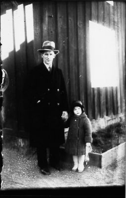 Man och flicka stående framför byggnad.
