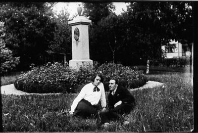 Man och kvinna sittande i gräset framför staty.
Nyckelord: Park Staty