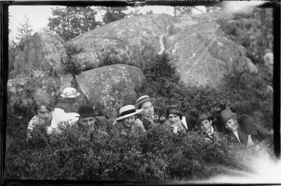 4 män och 3 kvinnor liggande framför berg.
