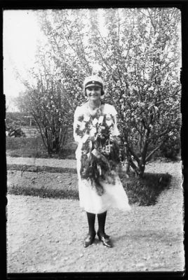 Kvinna stående med blommor runt halsen.
Nyckelord: Examen Blommor Grusgång
