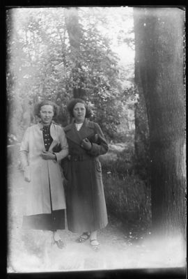 2 kvinnor stående i skogsbacke.
Nyckelord: Stig Träd