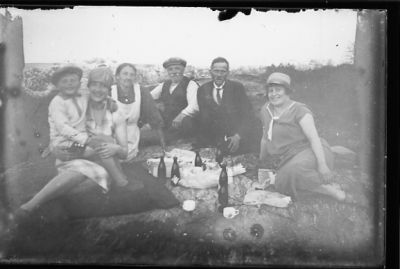 2 män, 3 kvinnor och 1 pojke sittande med picnickorg.
Nyckelord: Flaska Kaffe Picknic