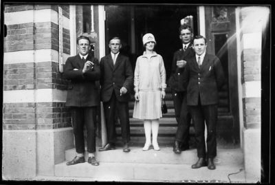 4 män och 1 kvinna stående på stentrappa till byggnad.
