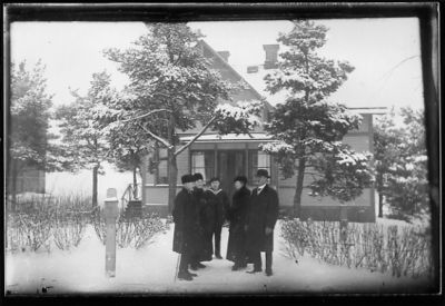 3 män och 2 kvinnor stående i snön framför byggnad.
Nyckelord: Vinter