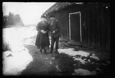 Man och kvinna stående framför ekonomibyggnad.
Nyckelord: Vinter