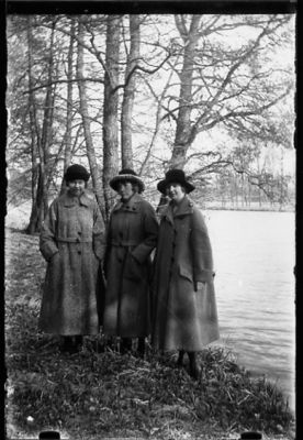 3 kvinnor stående intill vattendrag.
