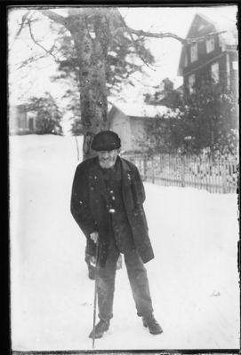 Man stående i snön med byggnad i bakgrunden.
Nyckelord: Vinter Käpp