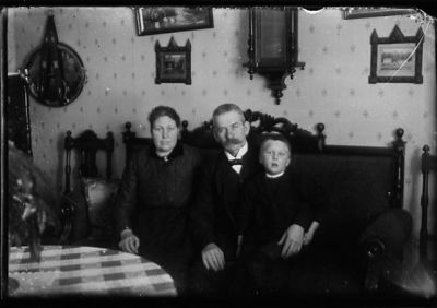 Man, kvinna och pojke sittande i soffa i rum.
Nyckelord: Klocka Tavla Tapet