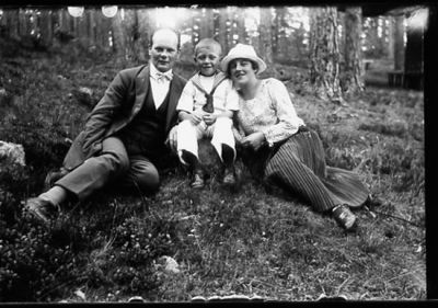 Man, kvinna och pojke sittande i skogsbacke.
Nyckelord: Skogsbacke