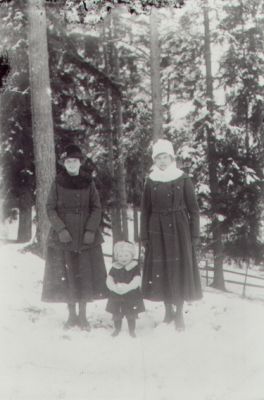 2 kvinnor och ett barn stående i skog.
Nyckelord: Skog Vinter