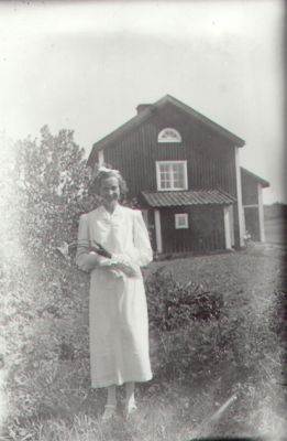Kvinna stående i trädgård.
Nyckelord: Trädgård