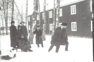 7 personer i snön framför byggnad.
Nyckelord: Vinter