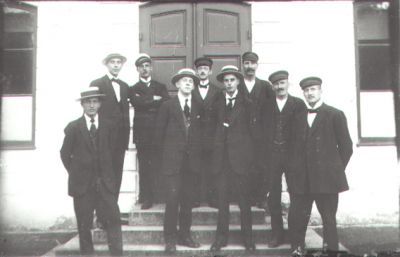 9 män stående på trappa till byggnad.
Nyckelord: Trappa Byggnad