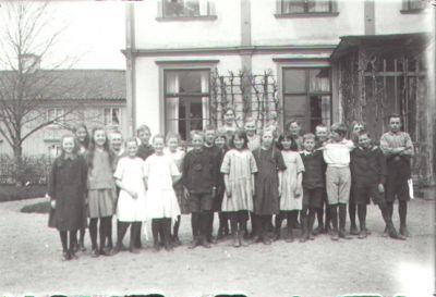 Skolklass med lärare stående framför byggnad.
Nyckelord: Skolklass