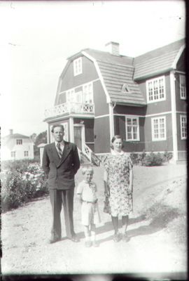 Man, kvinna och pojke stående framför byggnad.
Nyckelord: Balkong Trädgård