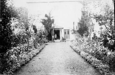 Trädgård med byggnad i bakgrunden.
Nyckelord: Rabatt