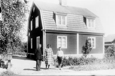 Man, kvinna och pojke stående framför byggnad.
Nyckelord: Postlåda