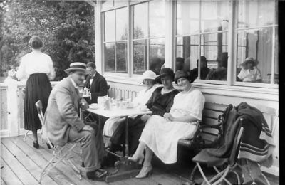 Man och 3 kvinnor sittande vid kaffebord i uteservering.
Nyckelord: Servering Veranda Kaffe