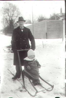 Man stående med spark som flicka sitter på.
Nyckelord: Spark Vinter