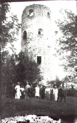 Ett antal personer stående framför ruin.
