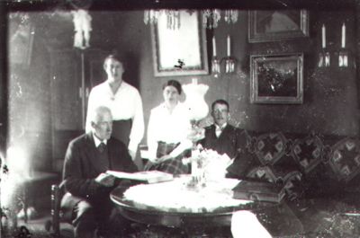 2 män och 1 kvinna sittande och 1 kvinna stående vid bord i finrum.
Nyckelord: Tavla Spegel Bok