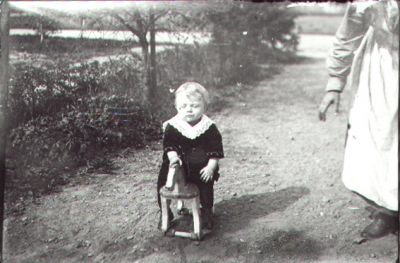 Barn sittande på trähäst.
Nyckelord: Leksakshäst