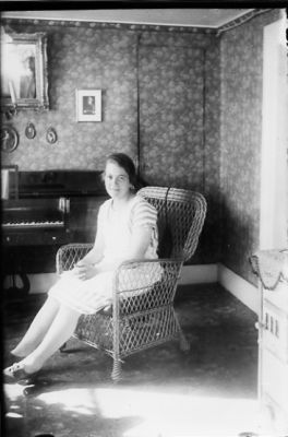 Kvinna sittande i korgstol i rum.
Nyckelord: Korgstol Piano Tapet