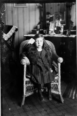 Flicka sittande i korgstol i rum.
Nyckelord: Korgstol Spegel