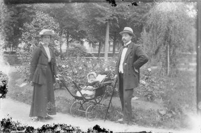 Man och kvinna stående i park med barvagn innehållande ett barn.
Nyckelord: Barnvagn Käpp