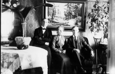 2 män och 1 kvinna sittande i finrum.
Nyckelord: Tavla