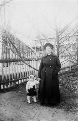 Kvinna och flicka stående i trädgård.
Nyckelord: Staket