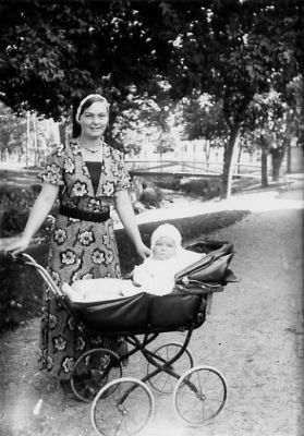 Kvinna stående med barnvagn innehållande ett barn.
Nyckelord: Barnvagn