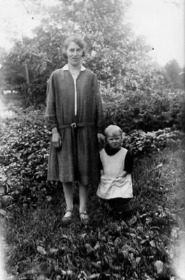 Kvinna och flicka stående i trädgård.
Nyckelord: Trädgård