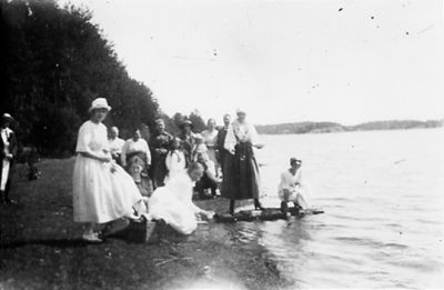 Ett antal personer samlade vid strandkant.
