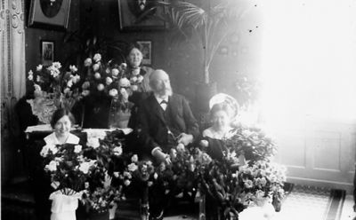 Man och 3 kvinnor sittande i rum med blommor.
Nyckelord: Blommor
