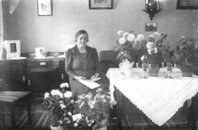 Kvinna sittande vid bord med blommor.
Nyckelord: Blommor
