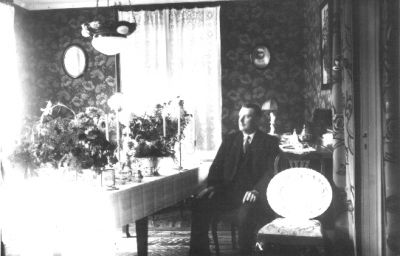 Man sittande vid bord med blommor.
Nyckelord: Blommor Tapet Lampa