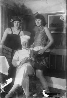 2 kvinnor stående och 1 sittande kvinna i rum.
Nyckelord: Pinnsoffa Tavla