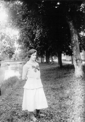 Kvinna stående intill vattendrag.
Nyckelord: Gräsmatta Transformator Bro