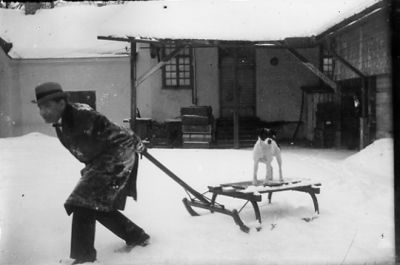 Man dragandes på kälke med hund stående på.
Nyckelord: Hund Kälke Vinter