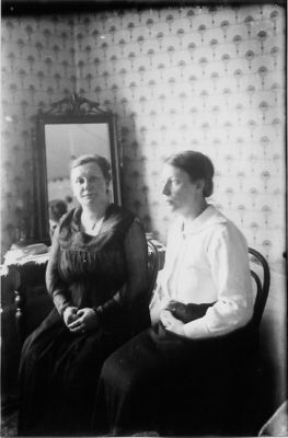 2 kvinnor sittande i rum.
Nyckelord: Spegel Interiör Tapet