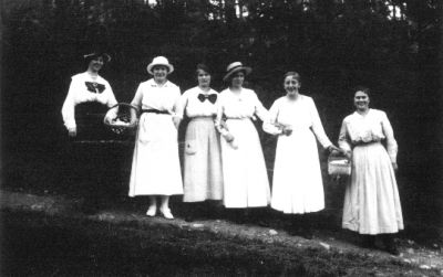 6 kvinnor stående i skogsbacke med picnickorgar.
Nyckelord: Skogsbacke Picnic