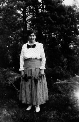 Kvinna stående i skogsbacke.
Nyckelord: Skog