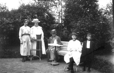 2 kvinnor och 1 pojke stående och 2 kvinnor sittande vid trädgårdsmöbler.
Nyckelord: Trädgårdsmöbel Växtlighet