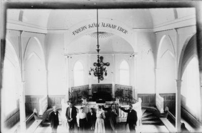 5 män och 2 kvinnor stående i kyrka.
