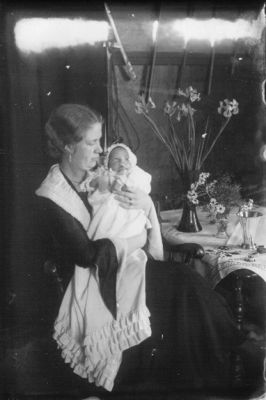 Kvinna sittande med baby i famnen.
Nyckelord: Blommor