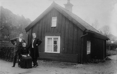 2 män och 1 kvinna utanför litan träbyggnad
