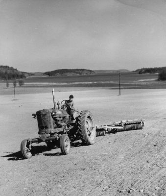 Traktor med vält på fält nära sjö
Nyckelord: Traktor