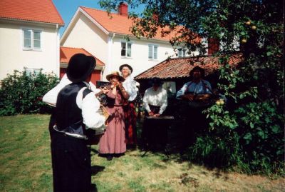 Orkester som spelar i trädgård
Nyckelord: Musikinstrument Dräkt